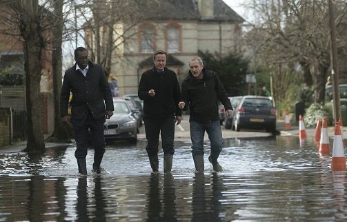 泰晤士河因河水猛涨导致部分河堤决堤，沿河地带形势严峻。首相卡梅伦（中）在泰晤士河畔视察灾区后表示，政府会尽全力救灾。