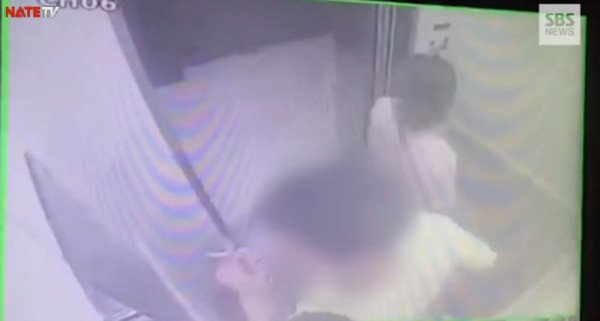 具荷拉站在自宅电梯里，男友一旁抽著菸。（图翻摄自SBS）
