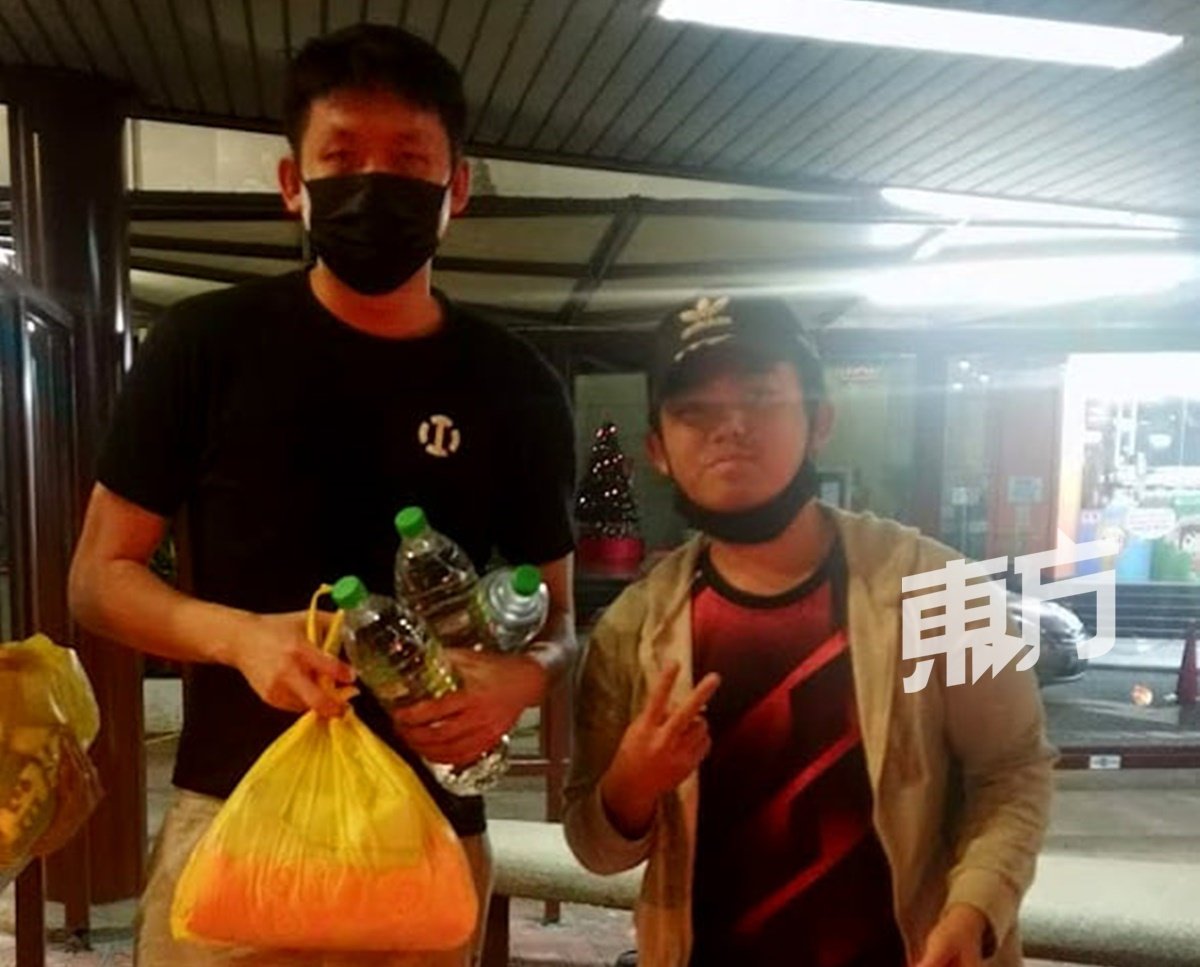 去年12月，蔡宜风（左）自发到街头派发物资给无家者，并与同样做出善行的陌生马来小贩合照。
