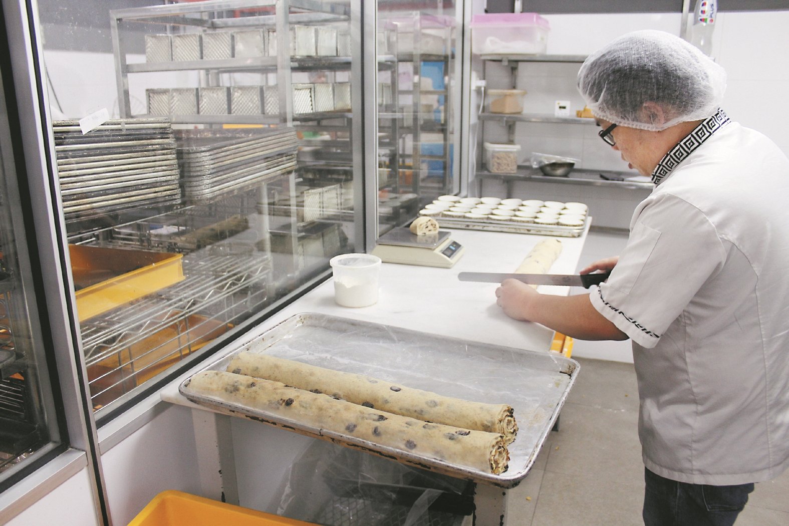 陈子杰师傅正在制作面包，谷品面包西糕的面包制作过程较复杂，最快需要6小时，最久需要7天。