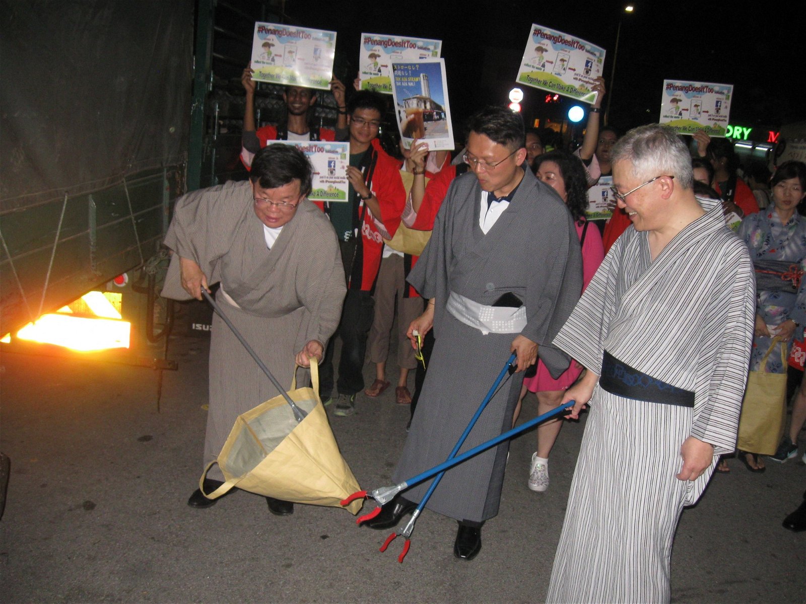 曹观友（左起）、杨顺兴和鹿屋真一郎，在槟城日本盆舞节现场拾垃圾。