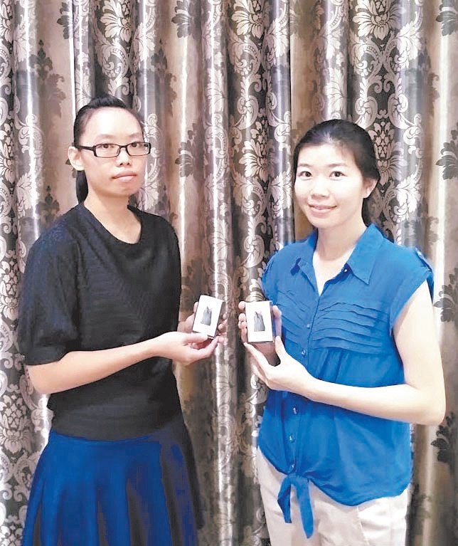 李思慧（左）和林湘湘展示太平第三医药制药厂， 以十八丁木炭和木醋液，创意生产的“黑金”活性炭皂。