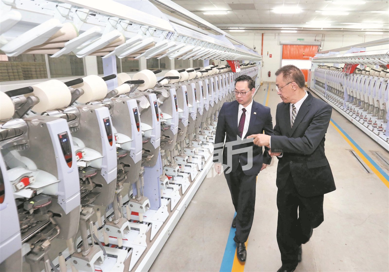 庄永良(右)向潘伟斯(左)，介绍该公司第二期厂房的自动化纺织设施。 （摄影：刘维杰）