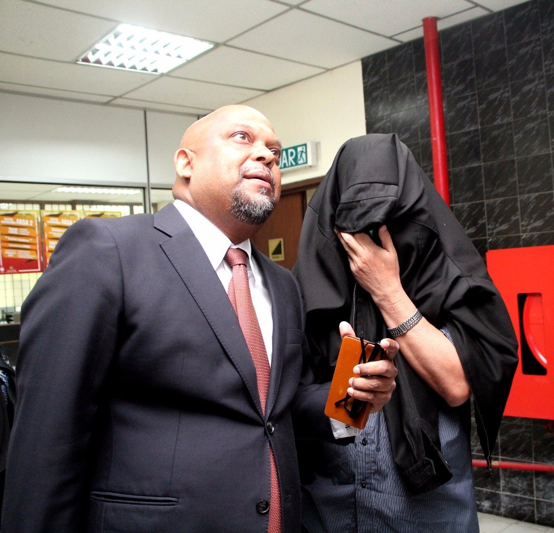 再努丁（右）用黑色外套遮住脸部，由律师纳斯卡兰陪同上庭面控。