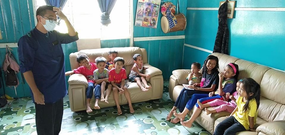 杨敦祥（左）在行管令期间派发援助金时，协助家徒四壁的单亲家庭，配合家具公司赠送沙发予该户家庭，图为孩子们雀跃不已，坐上沙发。