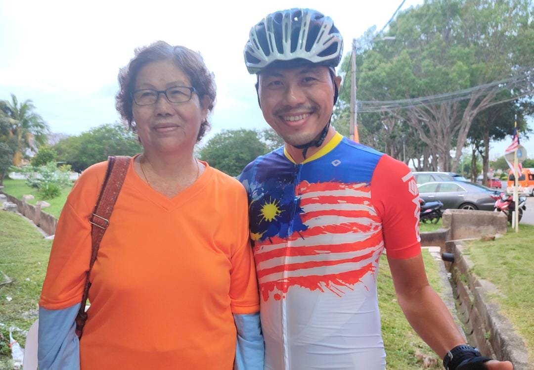 钟颖光（右）在出发骑单车环岛前，与前来打气的母亲罗桂云拍照留念。