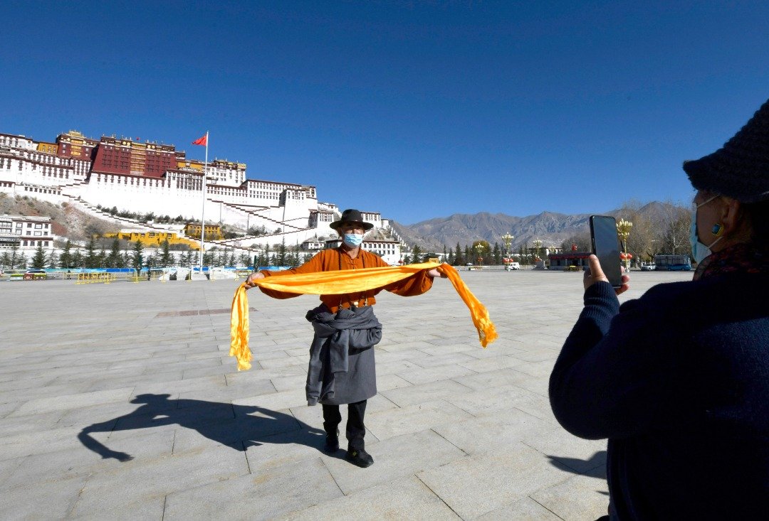 西藏拉萨布达拉宫广场，来自四川甘孜的参观者周四手捧哈达拍照留念。（图取自中新社）