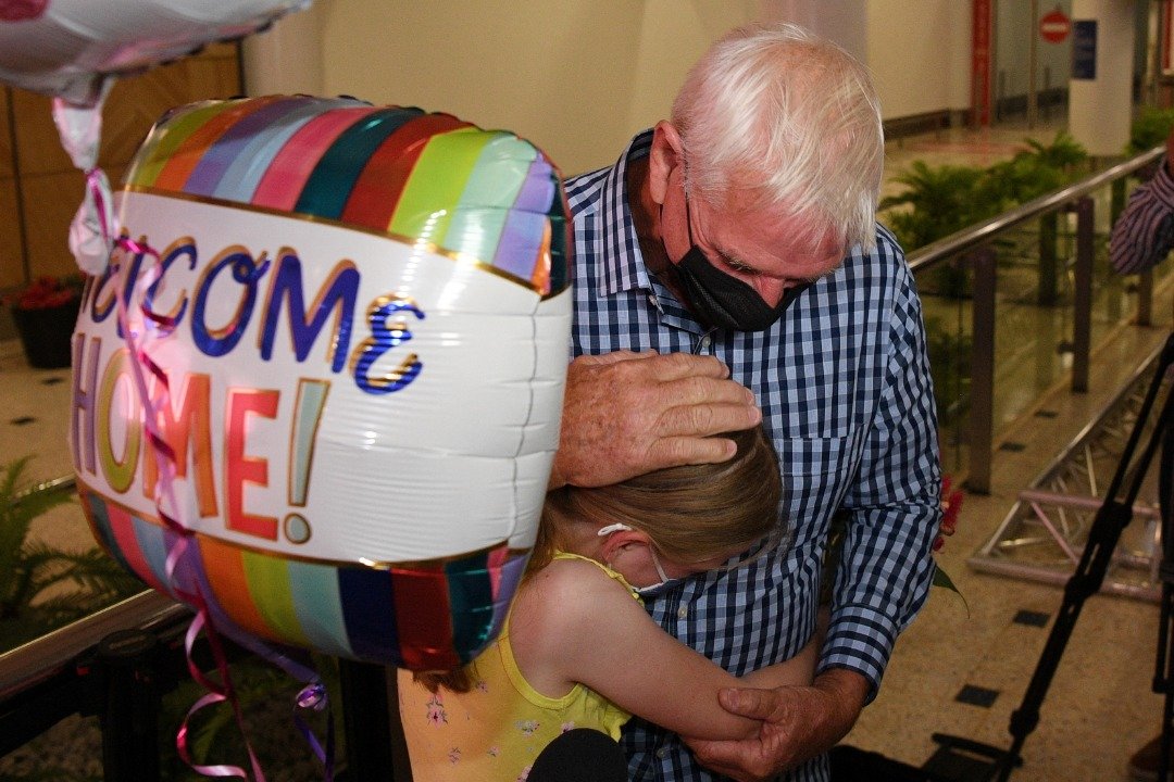 澳洲周一重开国门，8岁的小女孩伦普克一早就拿著欢迎气球在悉尼国际机场等候，在见到久违的外公后紧紧拥抱对方。（图取自澳联社/路透社）
