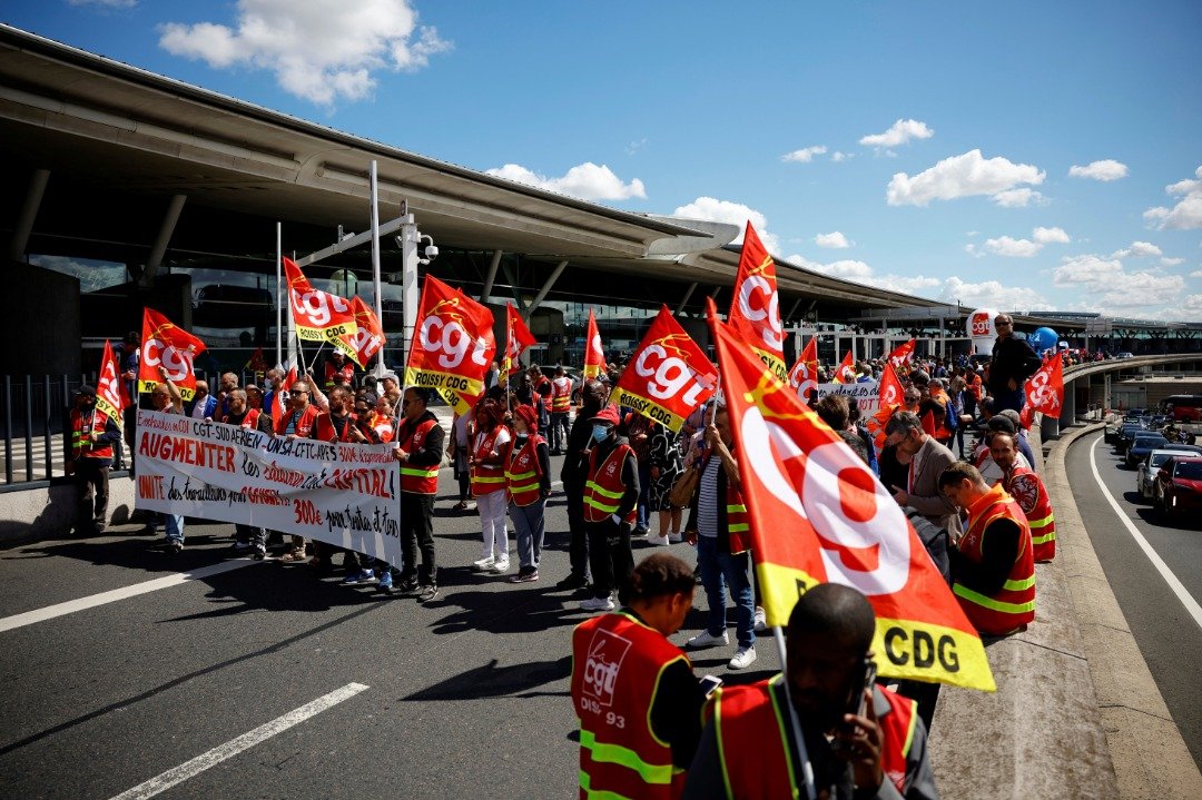 在法国巴黎戴高乐机场，罢工的机场员工本月1日举著法国CGT工会旗帜走出2F 航站楼，抗议法国通货膨胀导致的低工资。（图取自路透社）