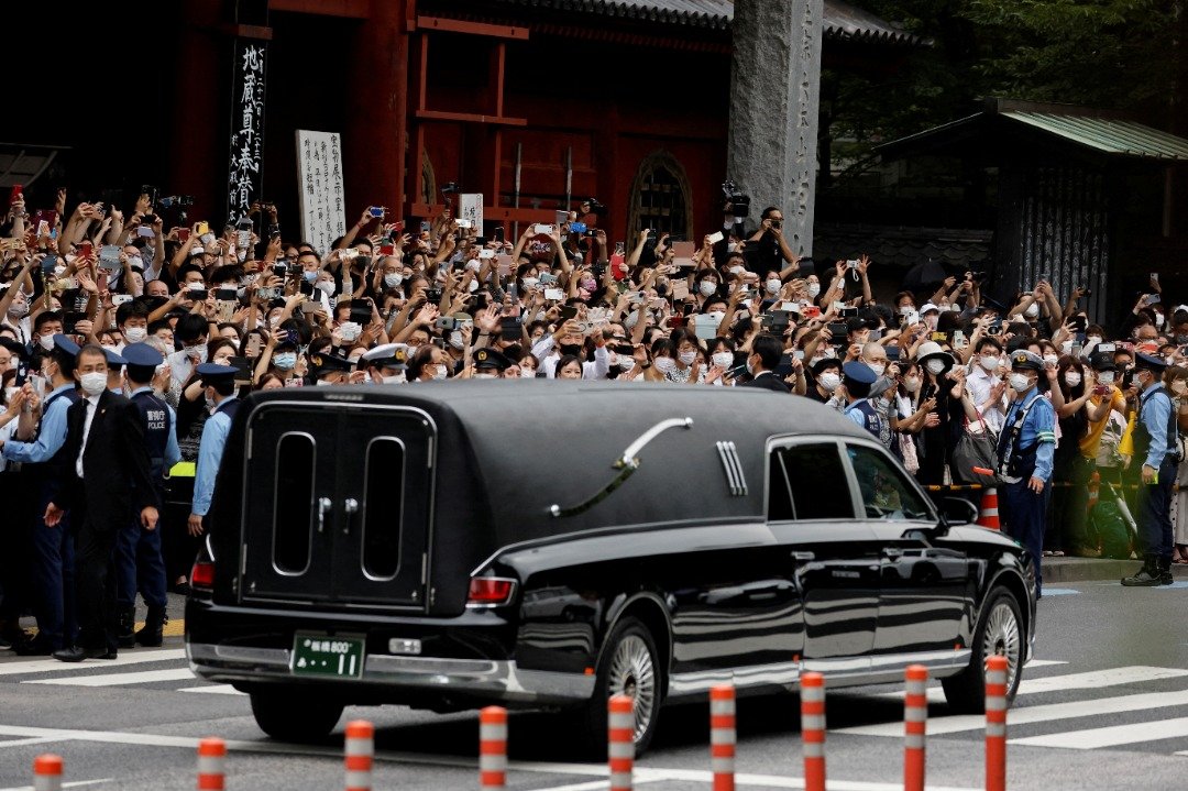 日本前首相安倍晋三遇刺身亡后，家属在本周二举行丧礼，当灵车驶出东京增上寺，许多民众在路边目送安倍离去，并举起手机拍照。（图取自路透社）