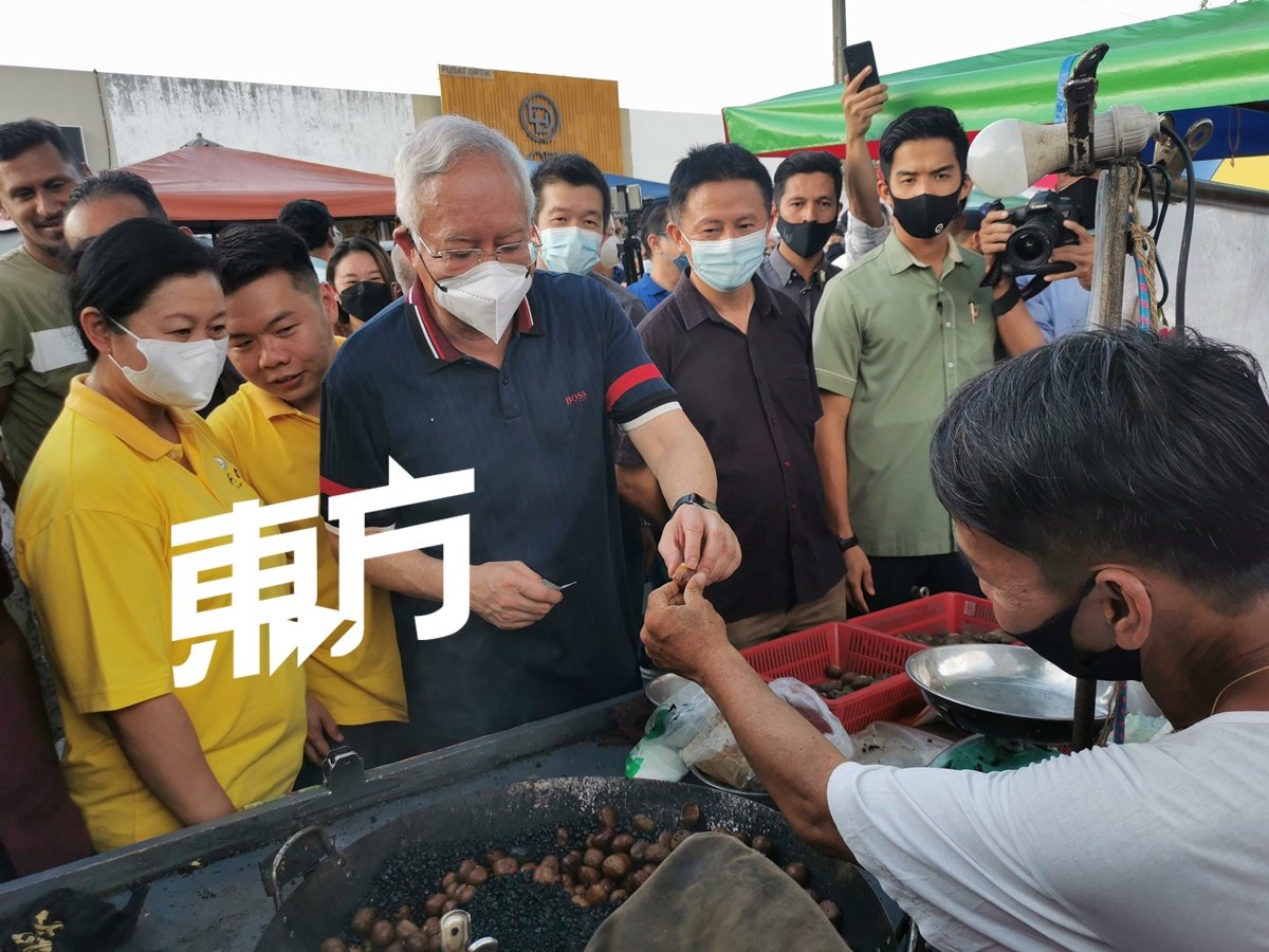 纳吉（左3）在造访碳炒栗子档口时，即场品尝栗子，左2起是刘国南及梁智伟。