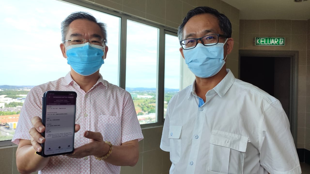 邱培栋（左）出示选委会的手机应用程式，呼吁选民检查选民册，右为刘志俍。