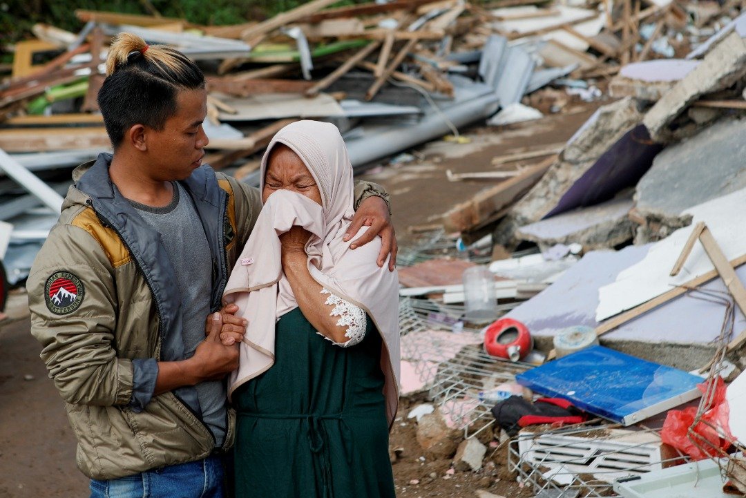一名妇女看到自己的房子在地震中形成废墟残骸，不禁悲从中来，家属在旁努力安慰。（图取自路透社）