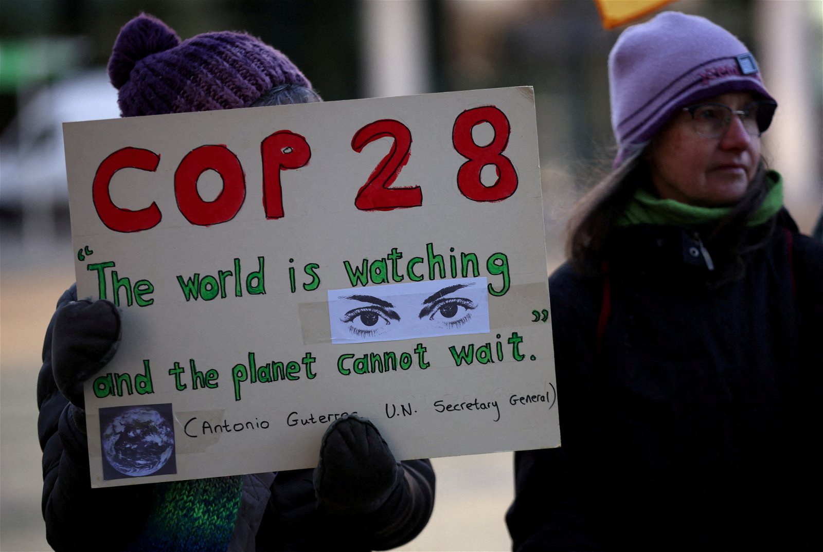 《联合国气候变化框架公约》第28次缔约方会议（COP28）当地时间周四开幕之际，英国一名气候活动家举著标语牌，引用联合国秘书长的话说：“全世界都在关注，地球已经等不及了”。