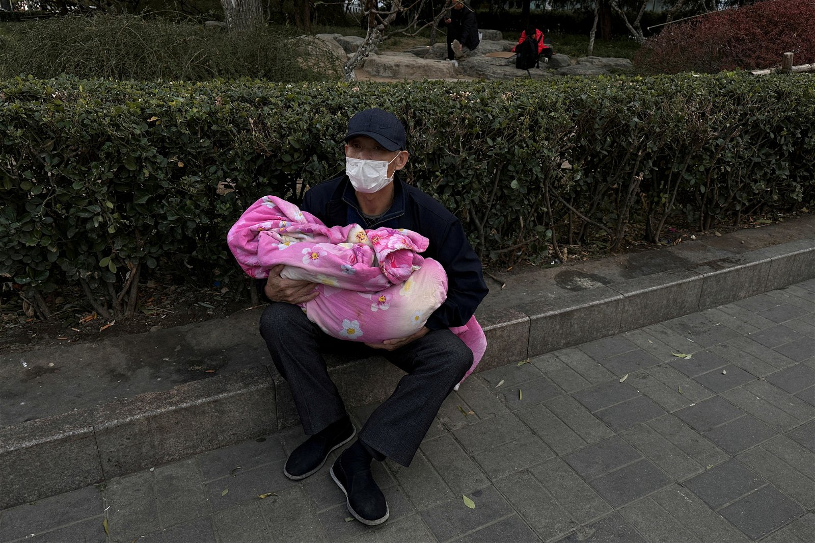 一名男子周一（11月27日）抱著一个孩子坐在儿童医院外。（图取自路透社）