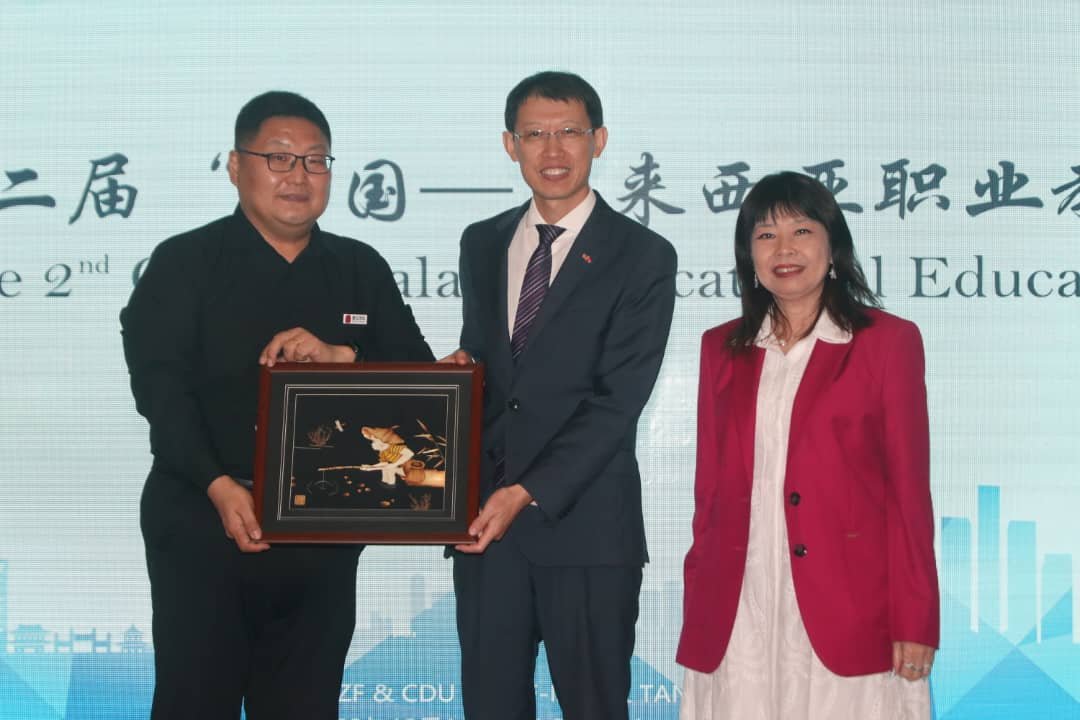 唐风国际教育集团代表庄雷（左）在副教长林慧英（右）的见证下，将纪念品赠予中国驻马大使馆参赞赵长涛（中）。