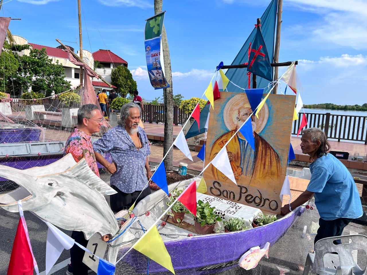 村民向邱培栋（左）讲解所装饰的渔船包含的意义。