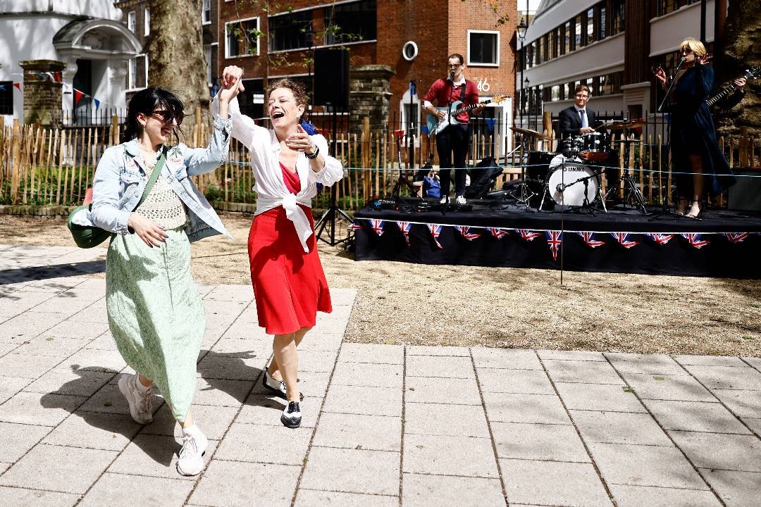 周日在英国伦敦圣詹姆斯教堂花园里举行的欢庆派对上，可见人们开心起舞。（图取自路透社）