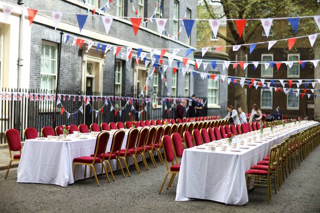 工作人员周日在英国伦敦唐宁街，为即将举行的“午餐盛会”活动做准备。英王查尔斯弟弟爱德华王子，他的妹妹安妮公主和比阿特丽斯公主，查尔斯另一个弟弟安德鲁王子的女儿尤金妮公主，将参加这场盛大的午宴，一同欢庆英王加冕典礼。（图取自路透社）