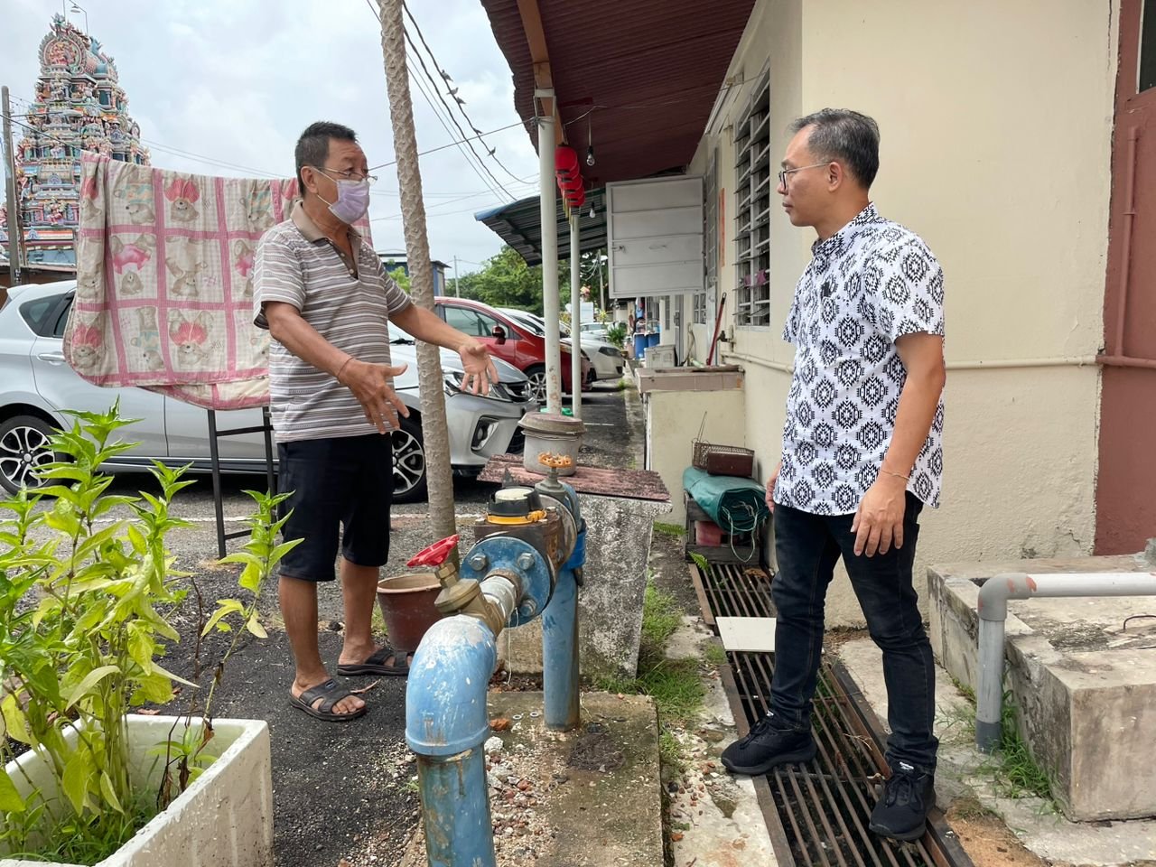 刘志俍（右起）向雅佳美浪组屋居民吴明标了解爆裂水管的情况。