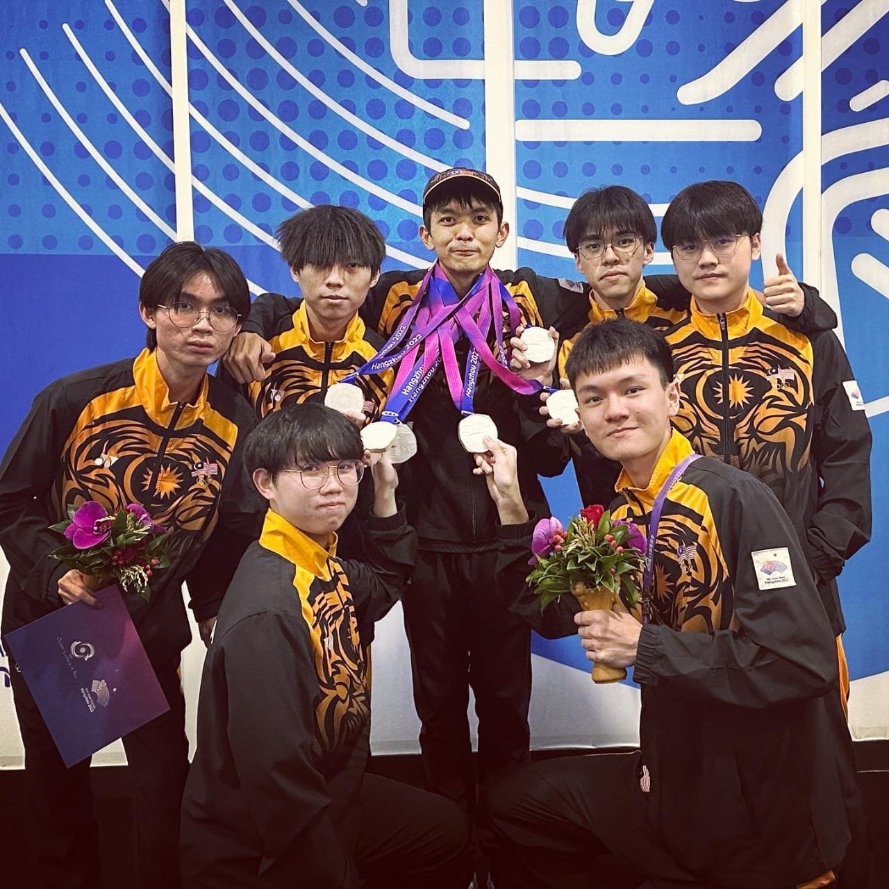 大马队教练与选手在杭州亚运会王者荣耀赛事荣获银牌后的合照。
