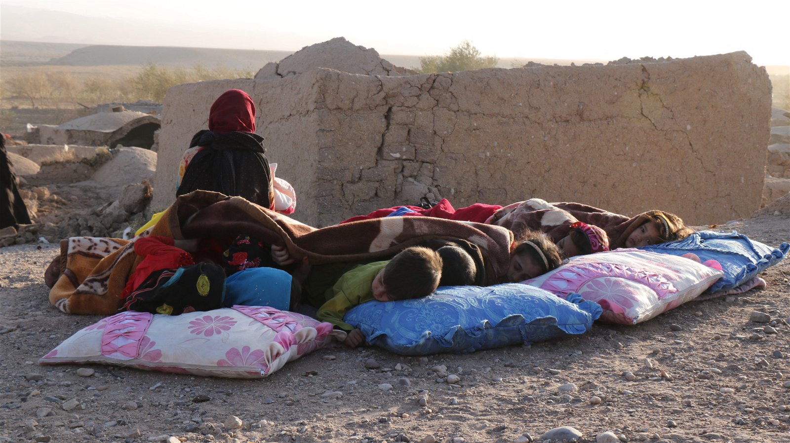 阿富汗赫拉特省儿童当地时间周六，在地震后受损的房子旁盖著毯子休息。（图取自法新社）