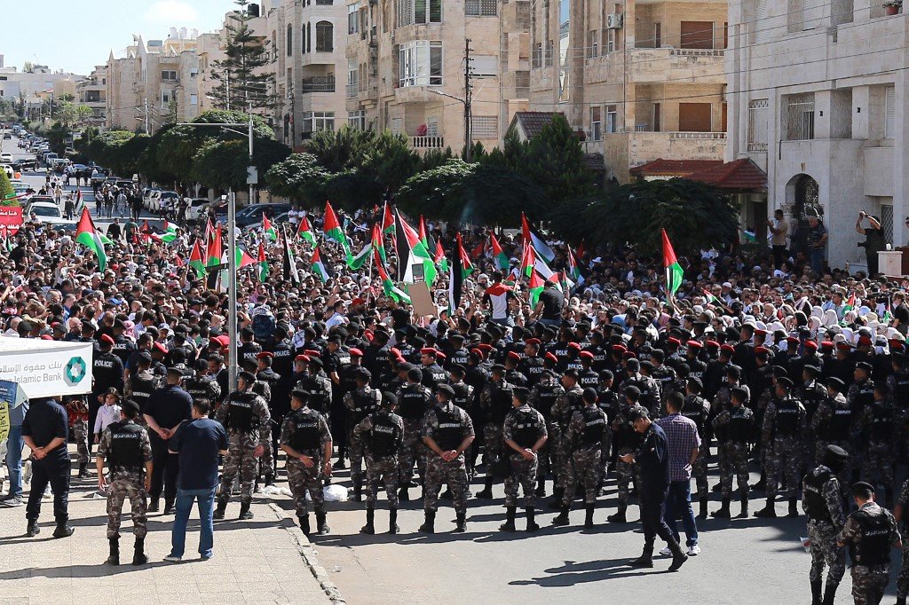 大批拿著巴勒斯坦旗的示威者上周五聚集在以色列驻安曼（前译阿曼）大使馆外抗议，安全部队人员筑起人墙，不让示威者靠近大使馆。（图取自法新社）