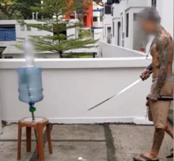 视频中，男子赤裸上身，身上满是文身，之间他挥动一把日本武士刀，然后将一个塑料瓶给一刀砍断。