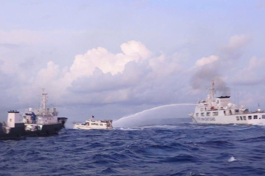 中国海警船（右）去年12月10日在南中国海仁爱礁水域，对菲律宾租用的补给船（中）使用水炮。（法新社/菲律宾海岸警卫队档案照）