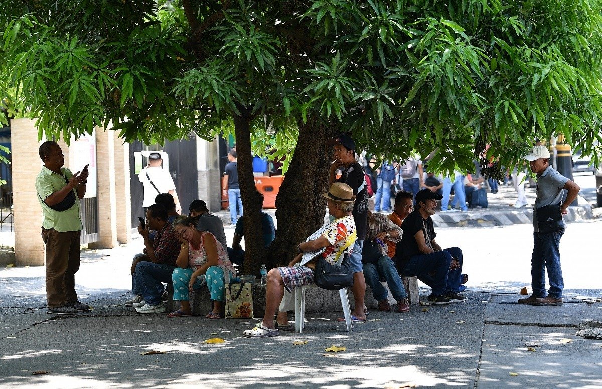 菲律宾天气近日异常炎热，图为周三，马尼拉市民在路边的树下遮荫乘凉。（图取自法新社）