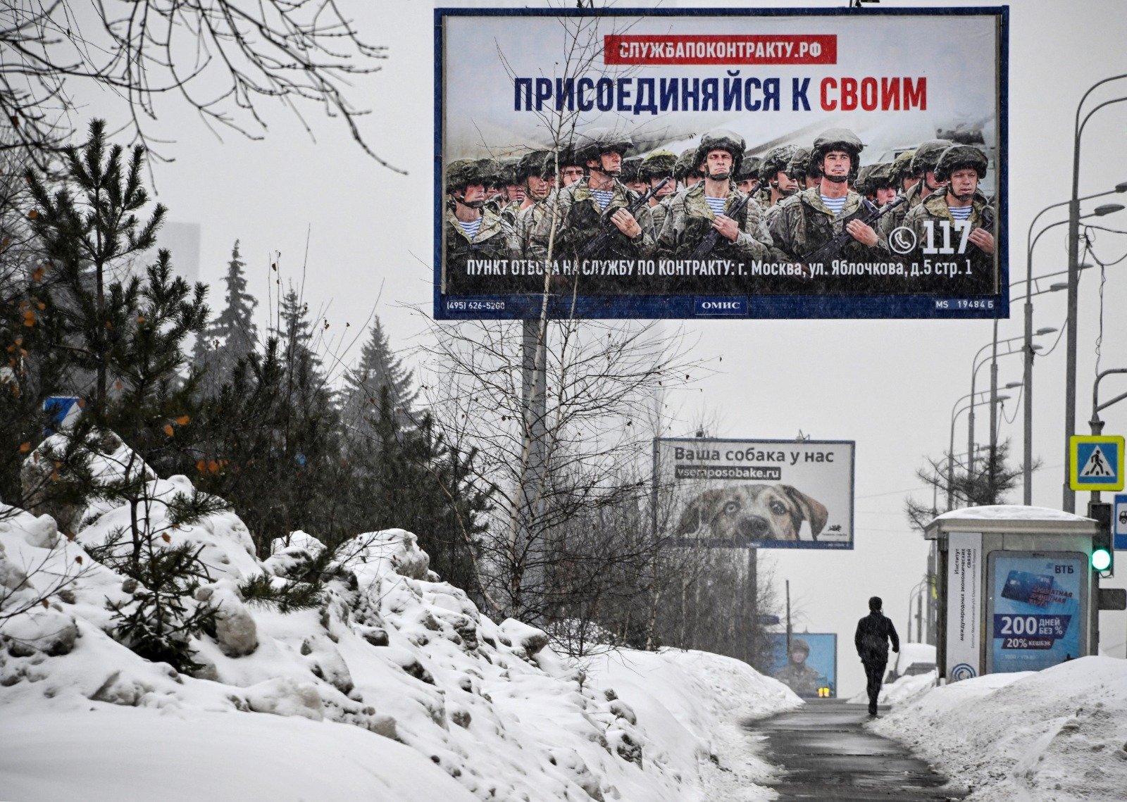 一名莫斯科居民周日走在宣传合约兵役的海报前，海报上写著“加入自己的军队”。（图取自法新社）