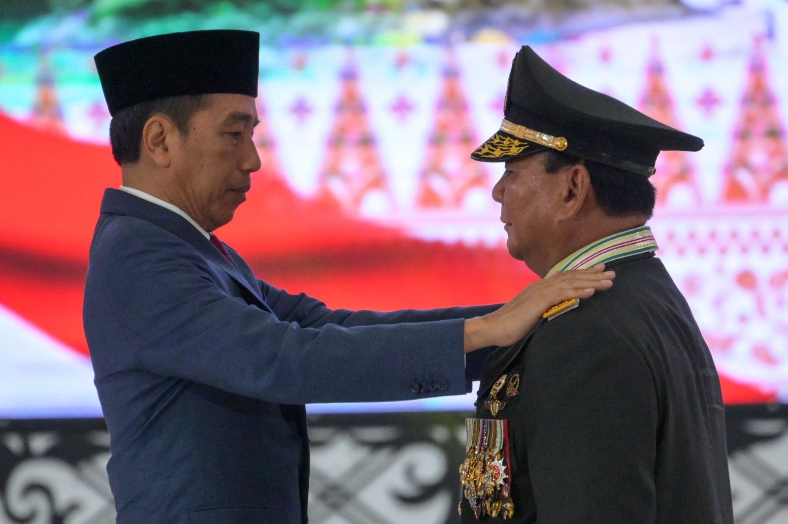 印尼总统佐科周三在雅加达国军总部授予下届准总统普拉博沃荣誉上将军衔，他为身穿军服的普拉博沃换下肩上的三星军衔，改配四星军衔肩章。（图取自法新社）