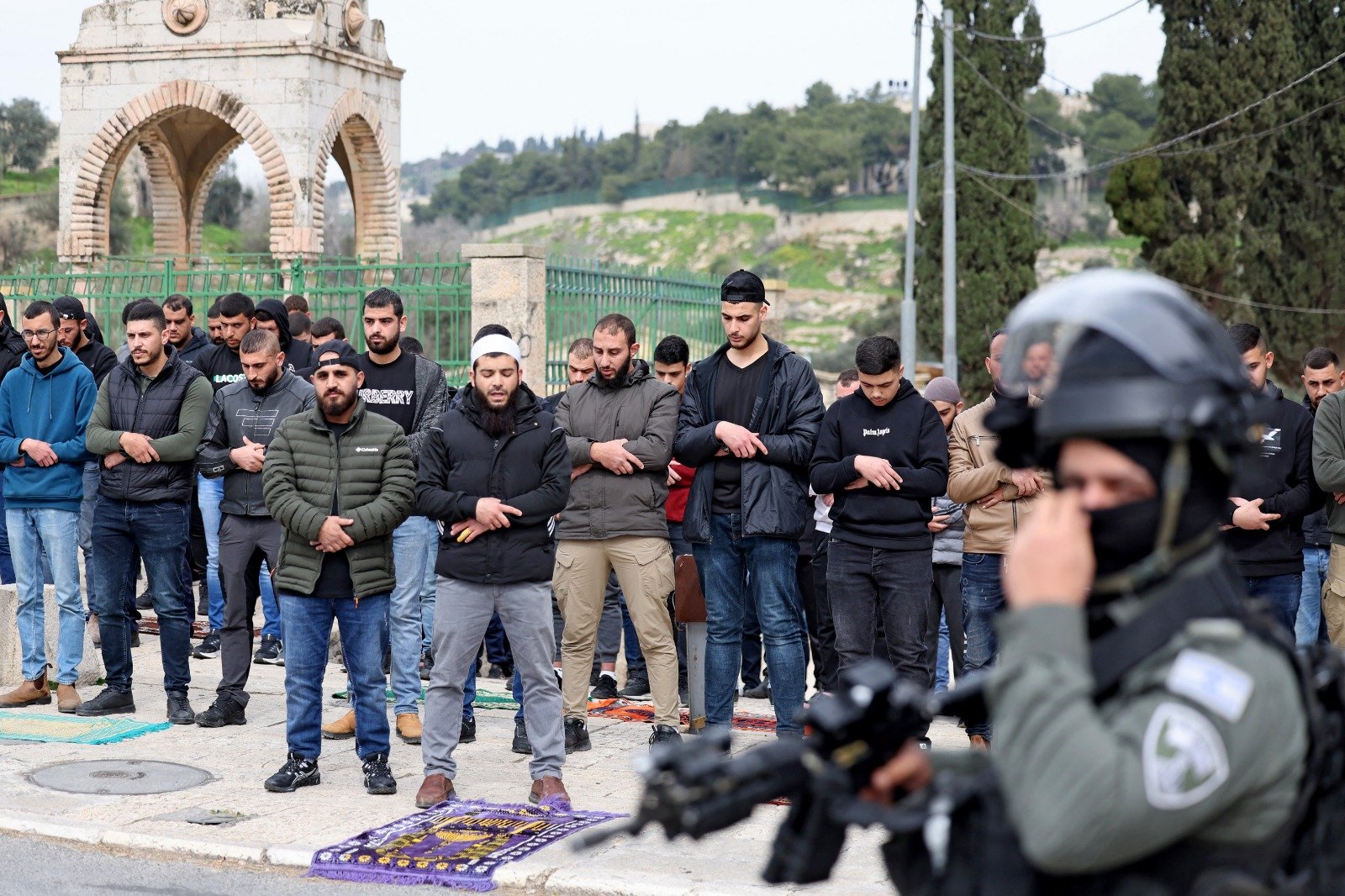 2月23 日，一群年轻的巴勒斯坦穆斯林男子在东耶路撒冷的一条街道上进行周五中午祈祷，而四周则驻守著全副武装的以色列安全部队人员在监视。随著以色列和哈马斯冲突持续，进入阿克萨清真寺大院实行了年龄限制。（图取自法新社）