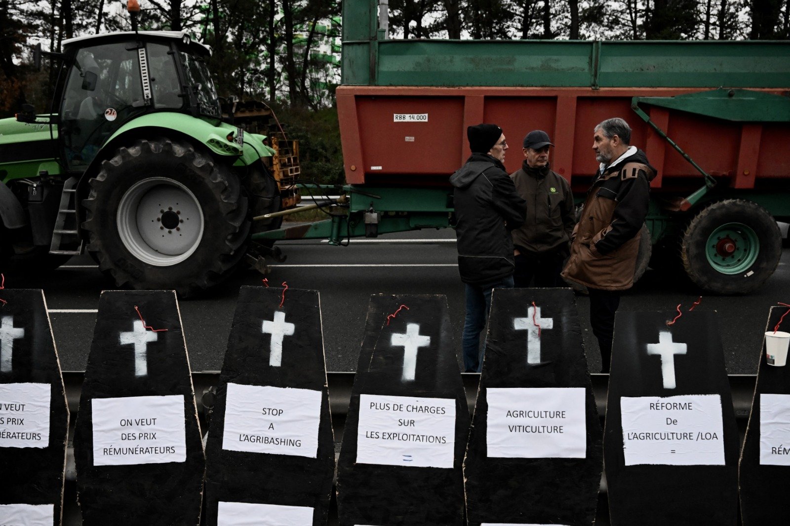 在法国西南部波尔多，农民周三封锁了波尔多的环路，站在用作抗议道具的假棺材旁。（图取自法新社）