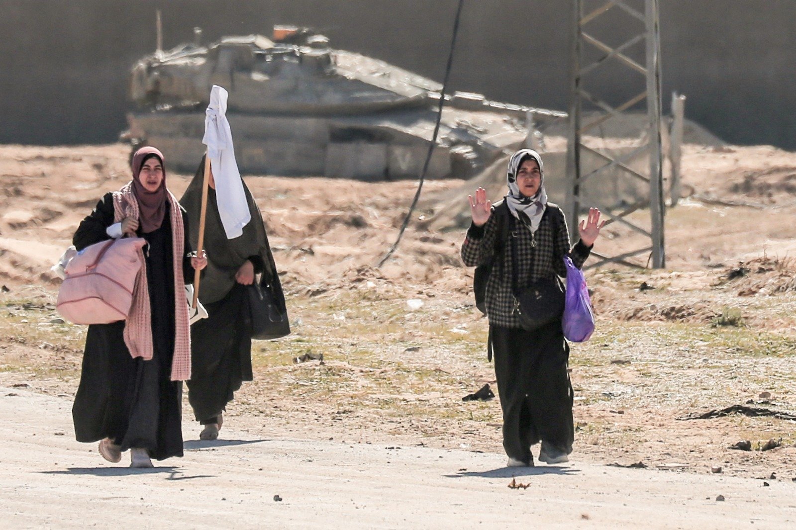数名巴勒斯坦妇女逃周二离加沙地带南部汗尤尼斯哈马德城地区时，她们背著财物举起一面白旗，走过以色列军队。（图取自法新社）