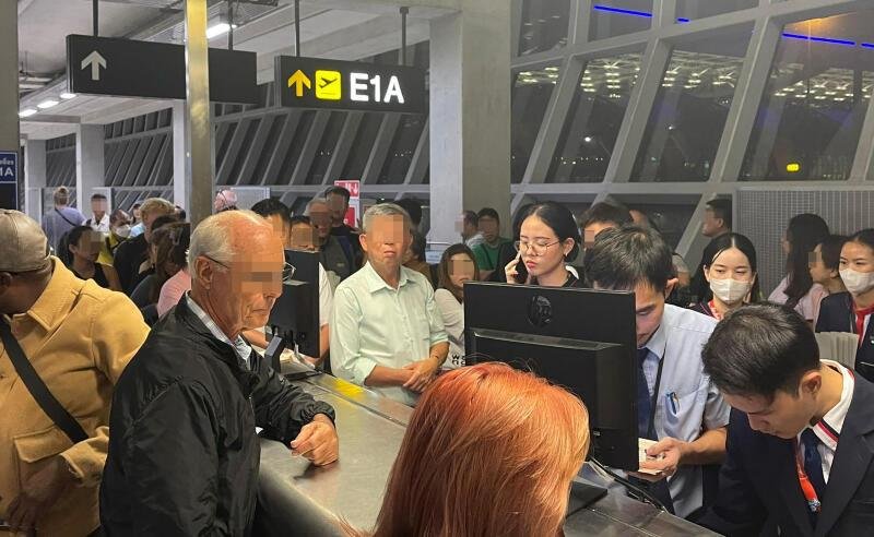 大批受影响乘客围著柜台，向机组人员询问和讨要说法。