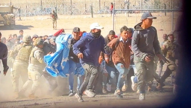 移民将国民警卫队成员撞倒，突破了防线，涌向边境墙。（视频截图）