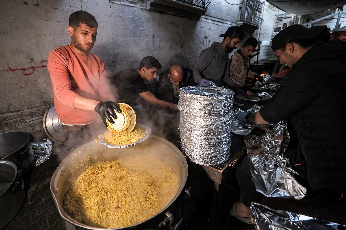 志愿者在加沙地带南部拉法的芭芭拉难民营，在上周日为斋月期间的加沙人提供餐食。（图取自法新社）