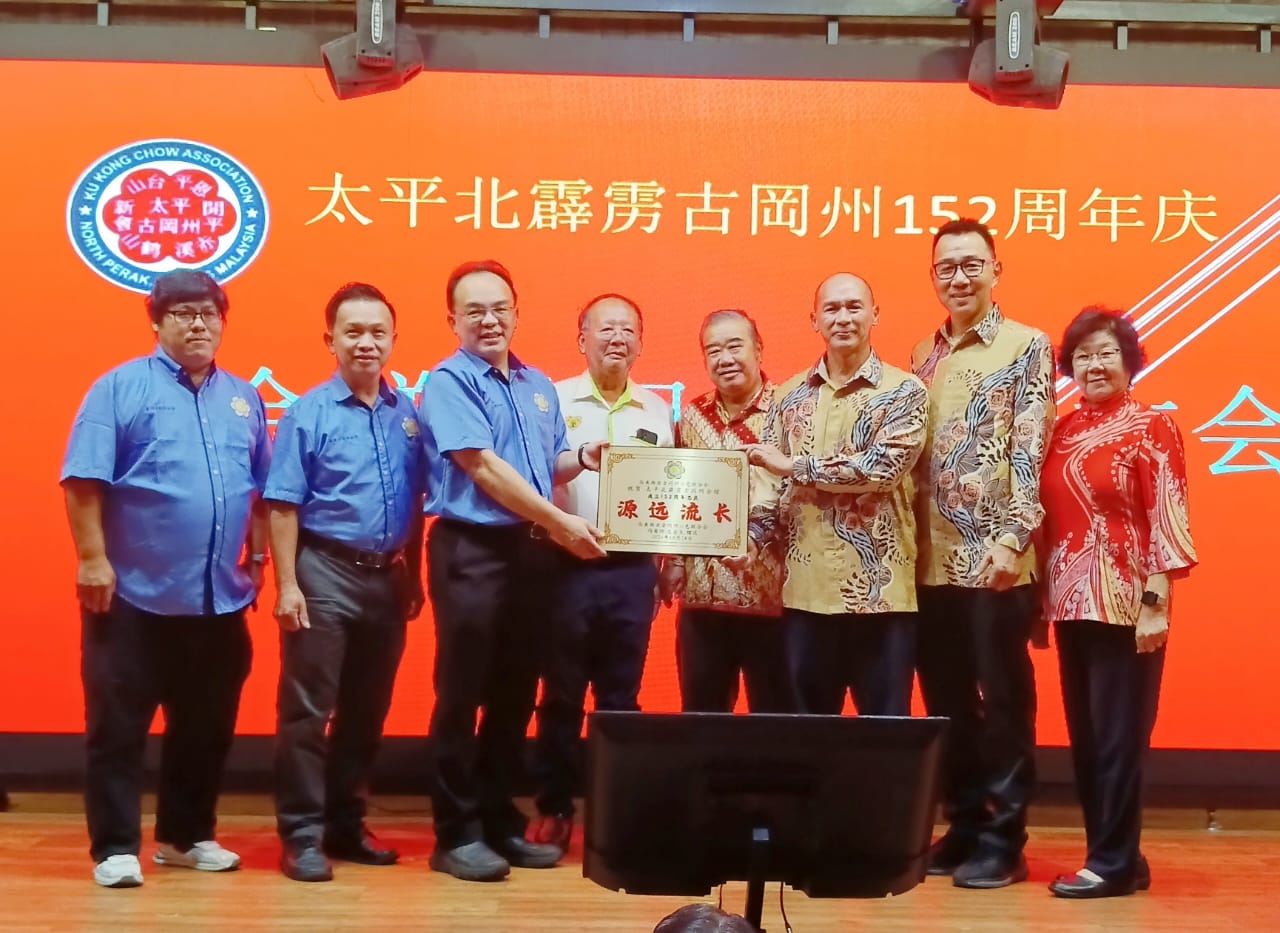 莫聪（左3）代表大马古冈州六邑联合会赠送贺周年庆纪念品予北霹雳古冈州会馆，由周广贤（左6）接领。