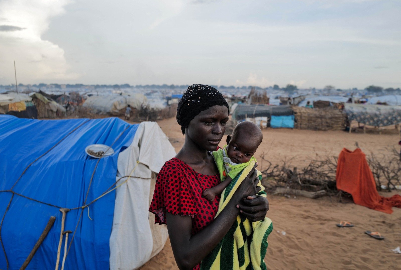 一名逃离苏丹达尔富尔地区的23岁母亲，本月5日在乍得阿德雷的临时住所旁，抱著她5个月大营养不良的孩子。（图取自路透社）