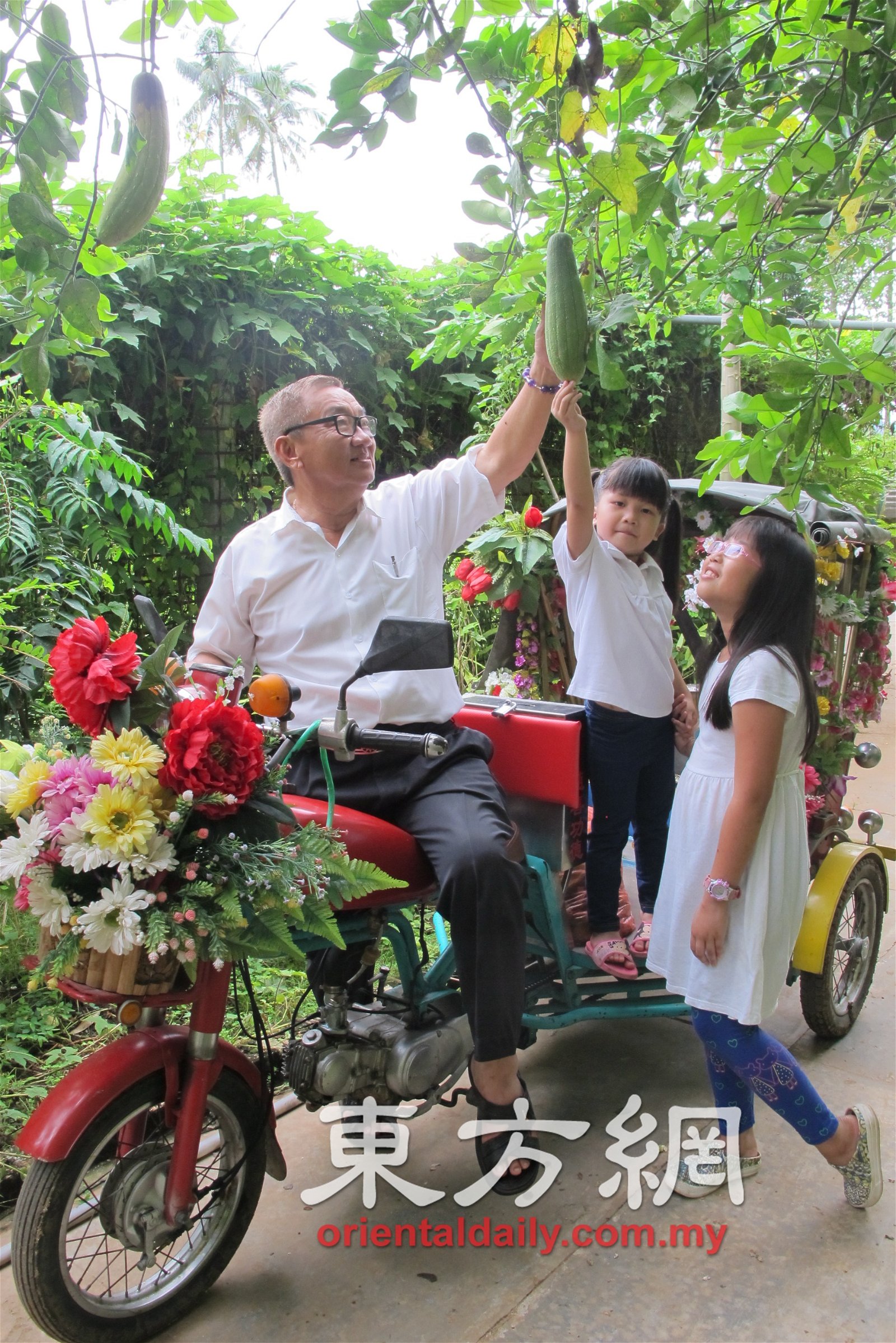 李添霖载著孩童欣赏长在竹藤下的丝瓜。