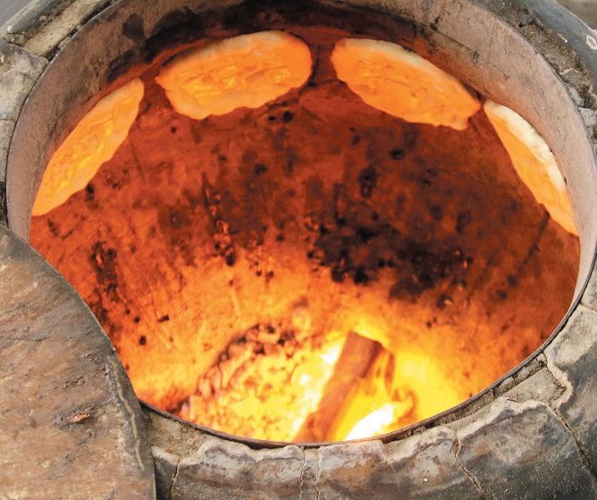 哈伦坚持传统，选择使用陶瓷缸并以火炭加热，再把一片片面饼抛入缸内烧烤，让印度面饼香味四溢。