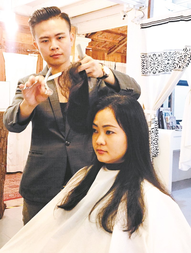 李俊辉为客户理发，依据个人头部塑造发型设计。