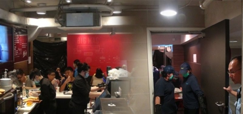 仵工从麦当劳抬走女尸，当时店内坐满大批食客。（图取自香港《苹果日报》）