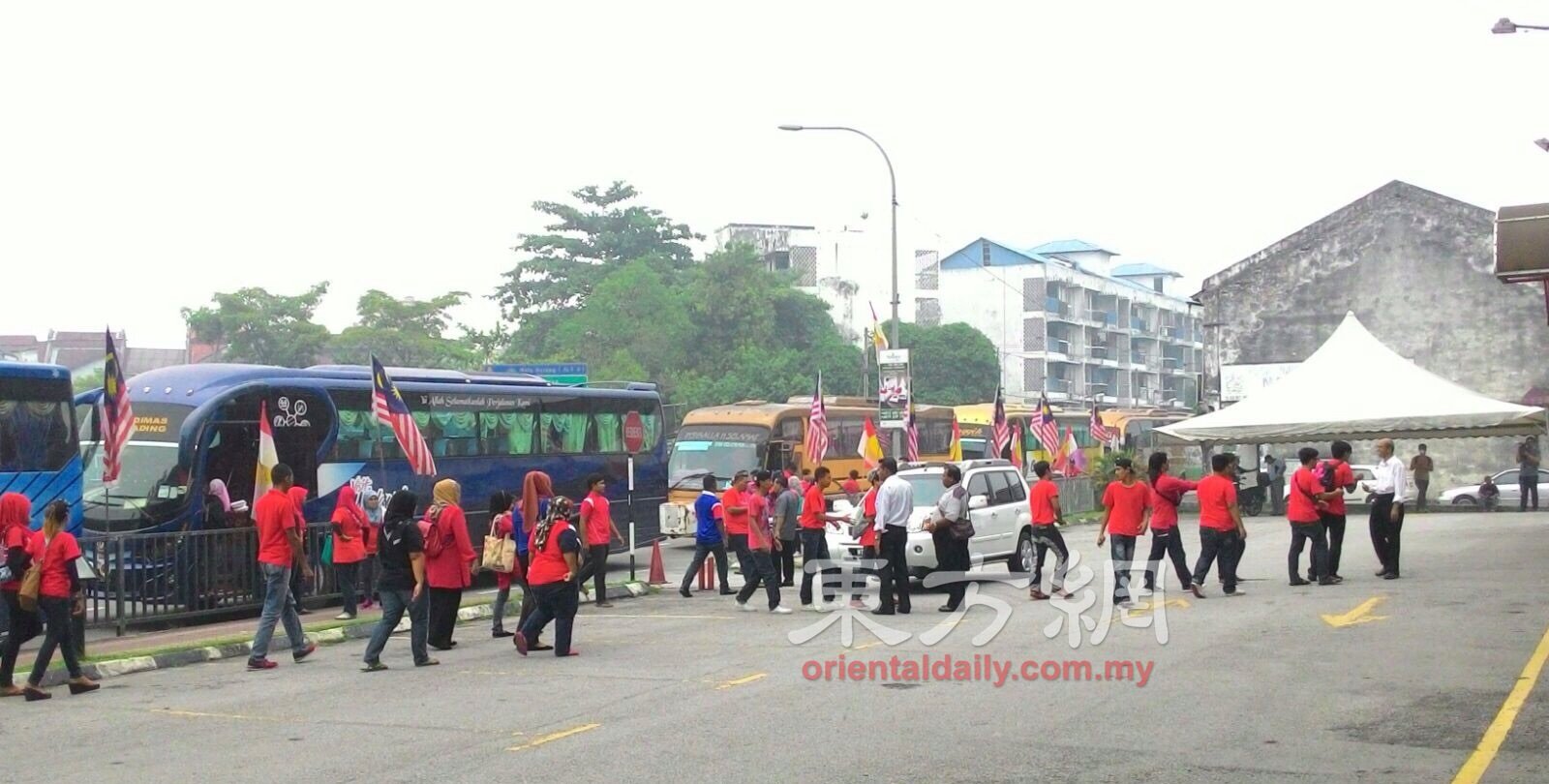 红衣人坐巴士陆续抵达集会地点。