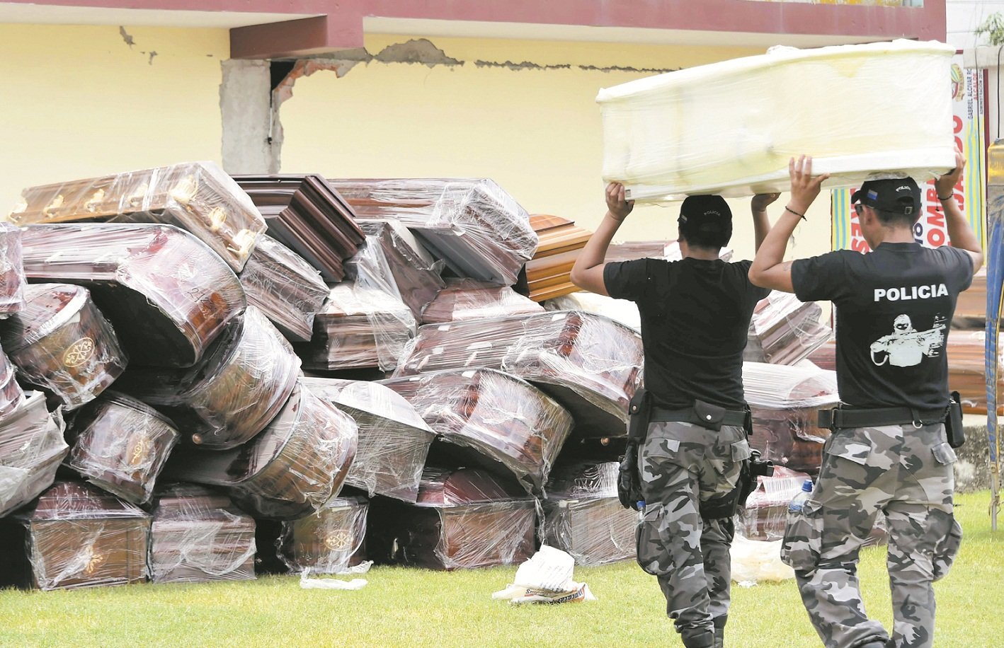 在受灾严重的佩德纳莱斯，警员将大量棺木集中放在球场上，以便灾民安置离世的亲人。