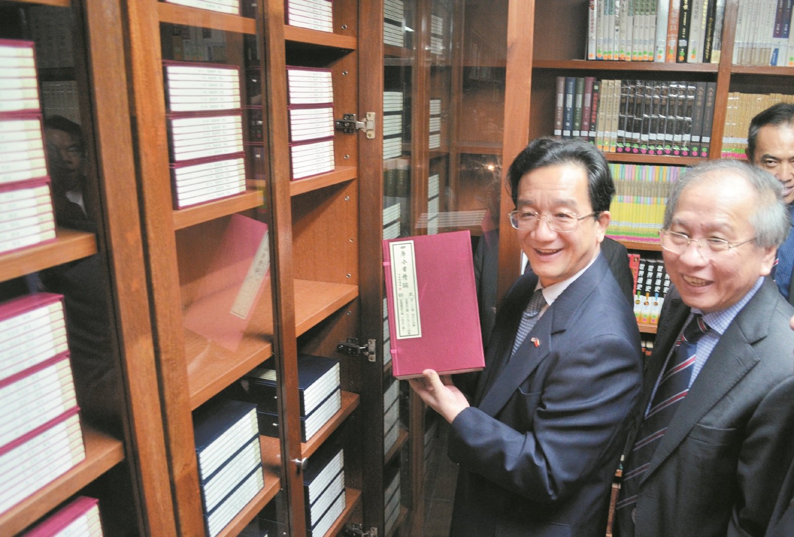 黄惠康（左）在许廷炎陪同下，将《四库全书》亲手收入华堂图书馆书橱中。