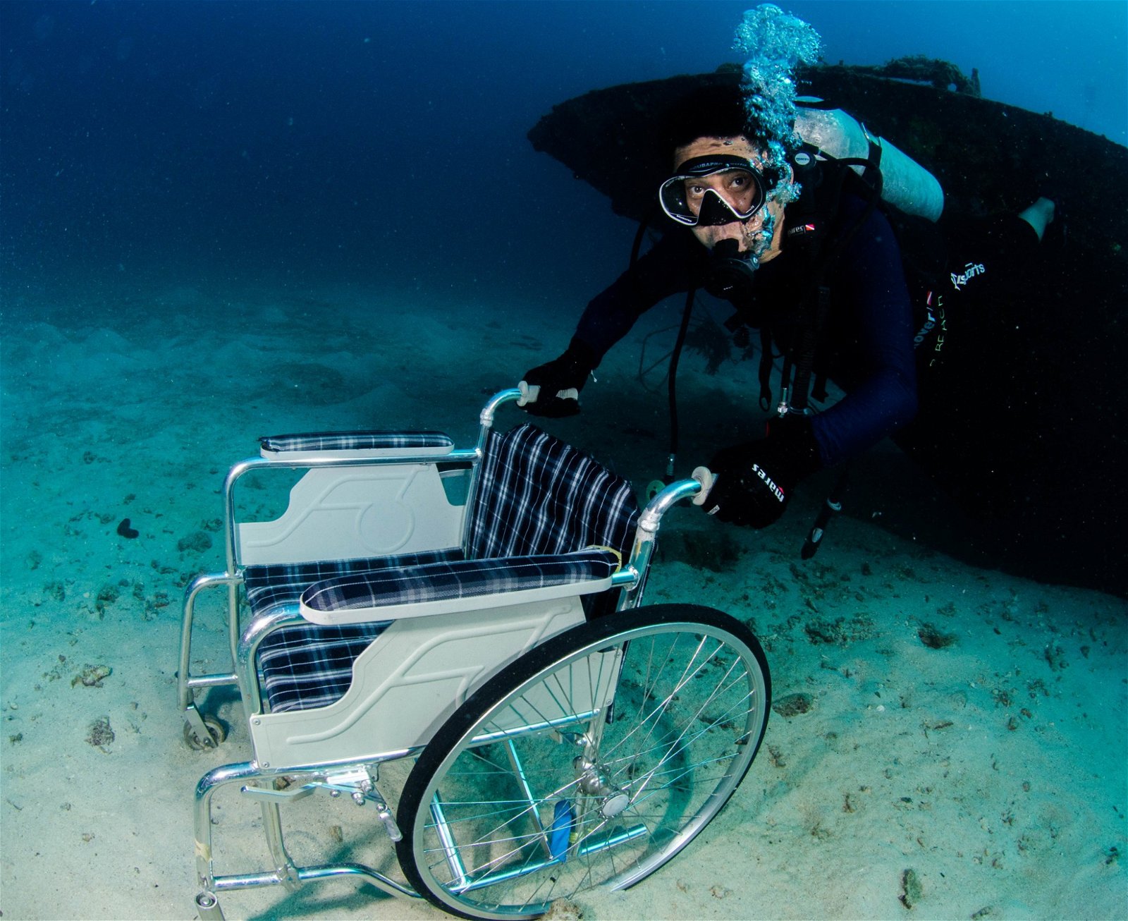 特友下到海里，外观和一般人无异，因此特意把轮椅带下海，留影纪念。