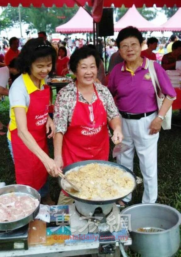林开舅（中）靠经验练就煮出百人食物份量，图为她与乡亲在海南村义卖会时的合照。