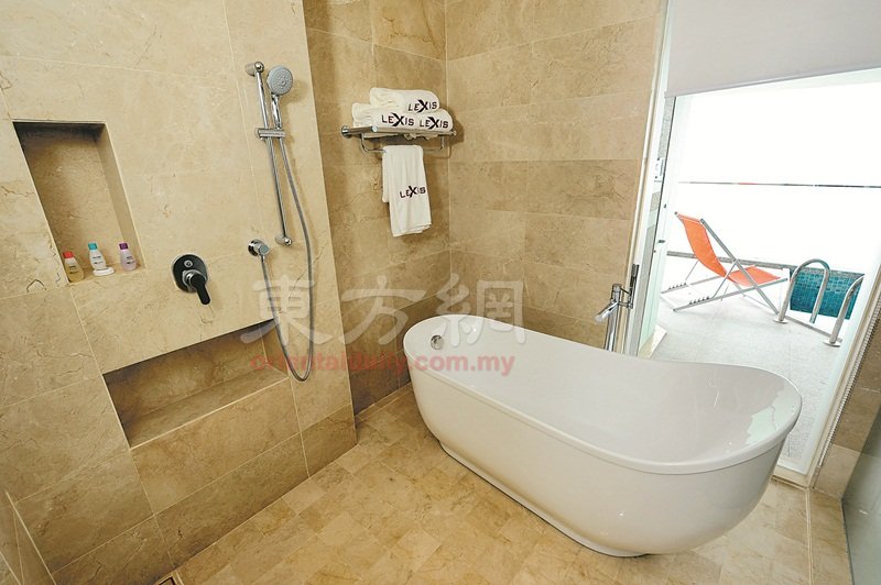 浴室的浴缸前设有一个落地窗，让住客可以边泡澡边瞭望著一望无际的海景。